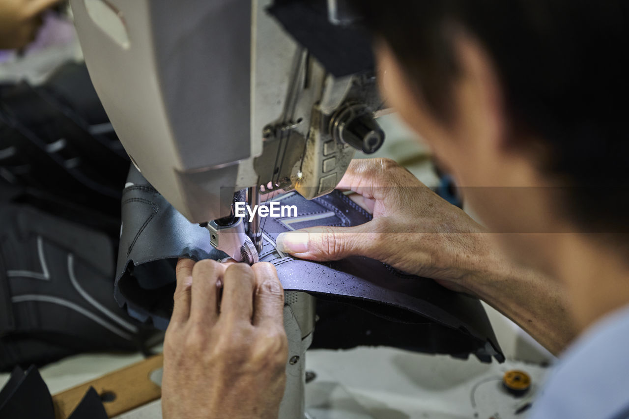 Detail of worker's hands doing sewing in the leather of the shoes at chinese shoes factory