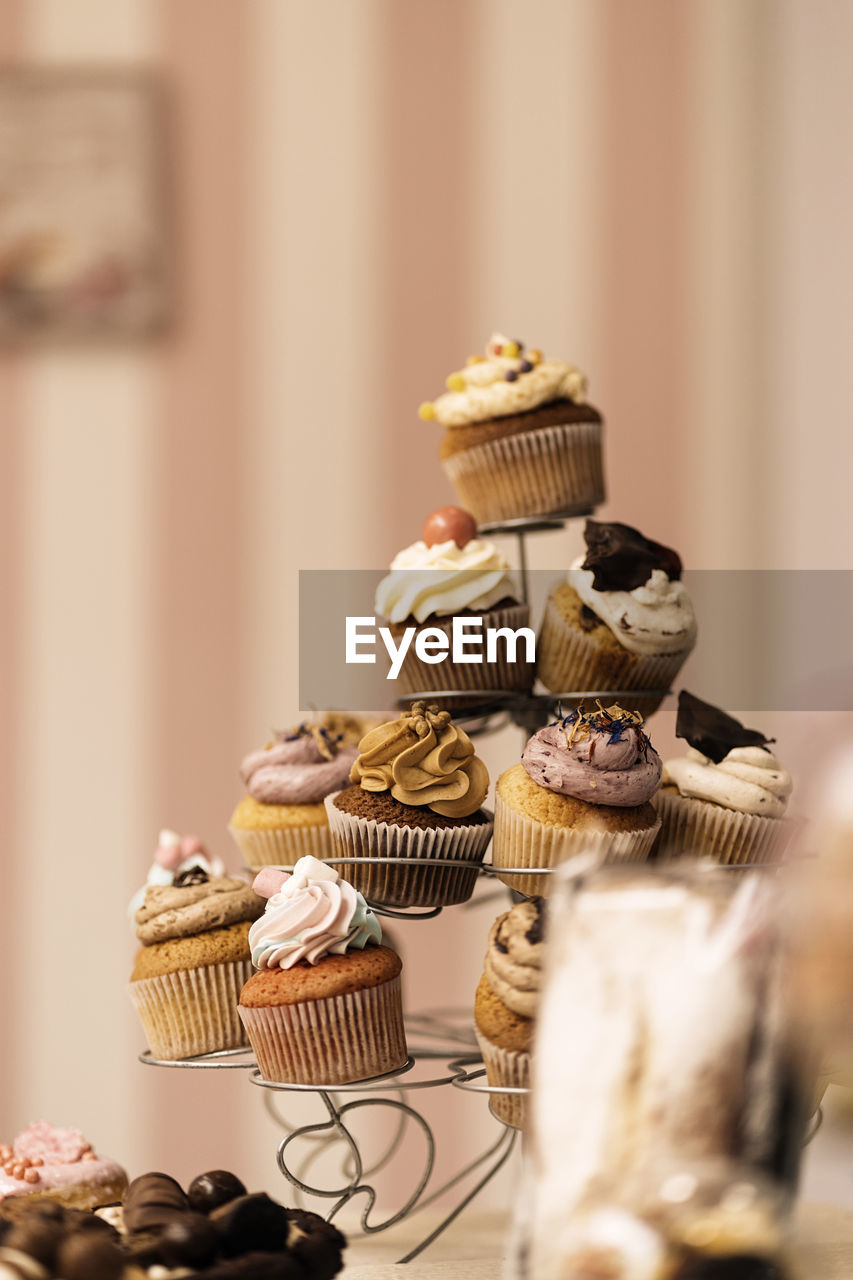 Bunch of assorted tasty cupcakes placed on metal holder on table in bakery