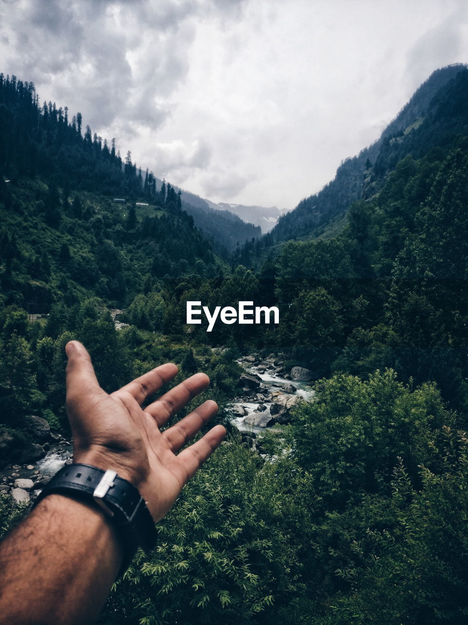 Cropped hand of person against mountains