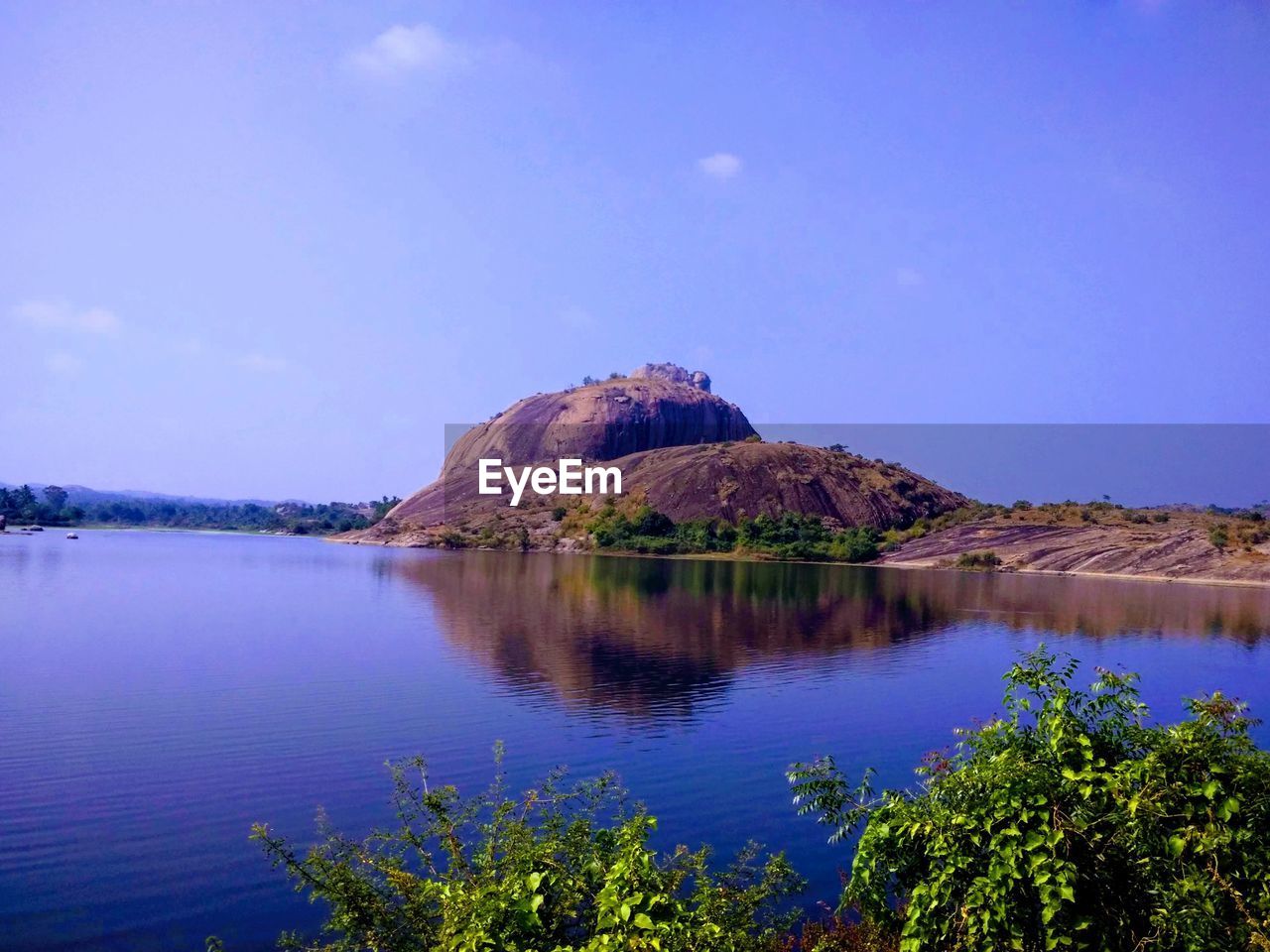 Scenic view of lake and mountains against blue sky