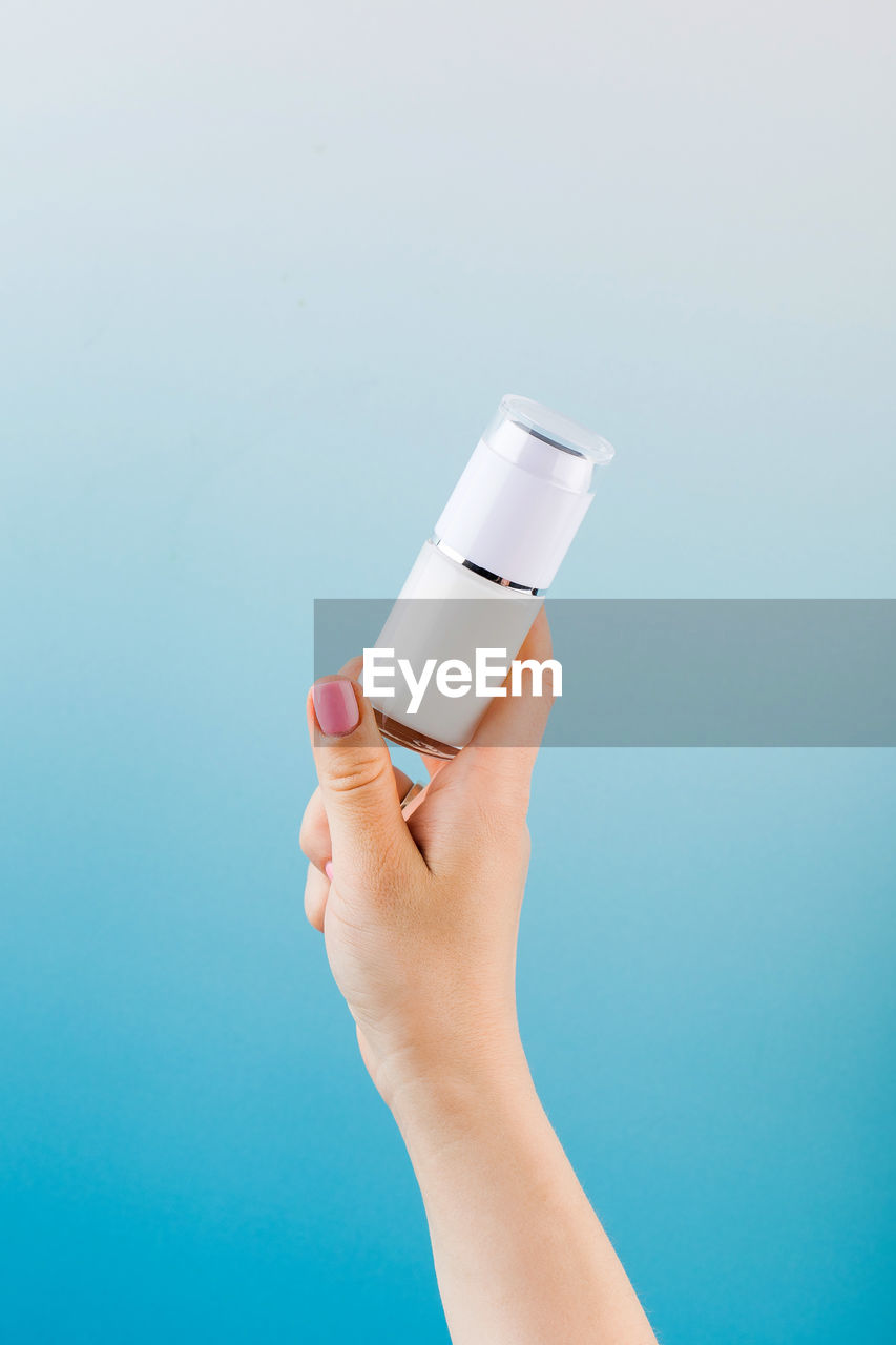 A mock-up of a jar of moisturizer in a woman's hand on a blue background.