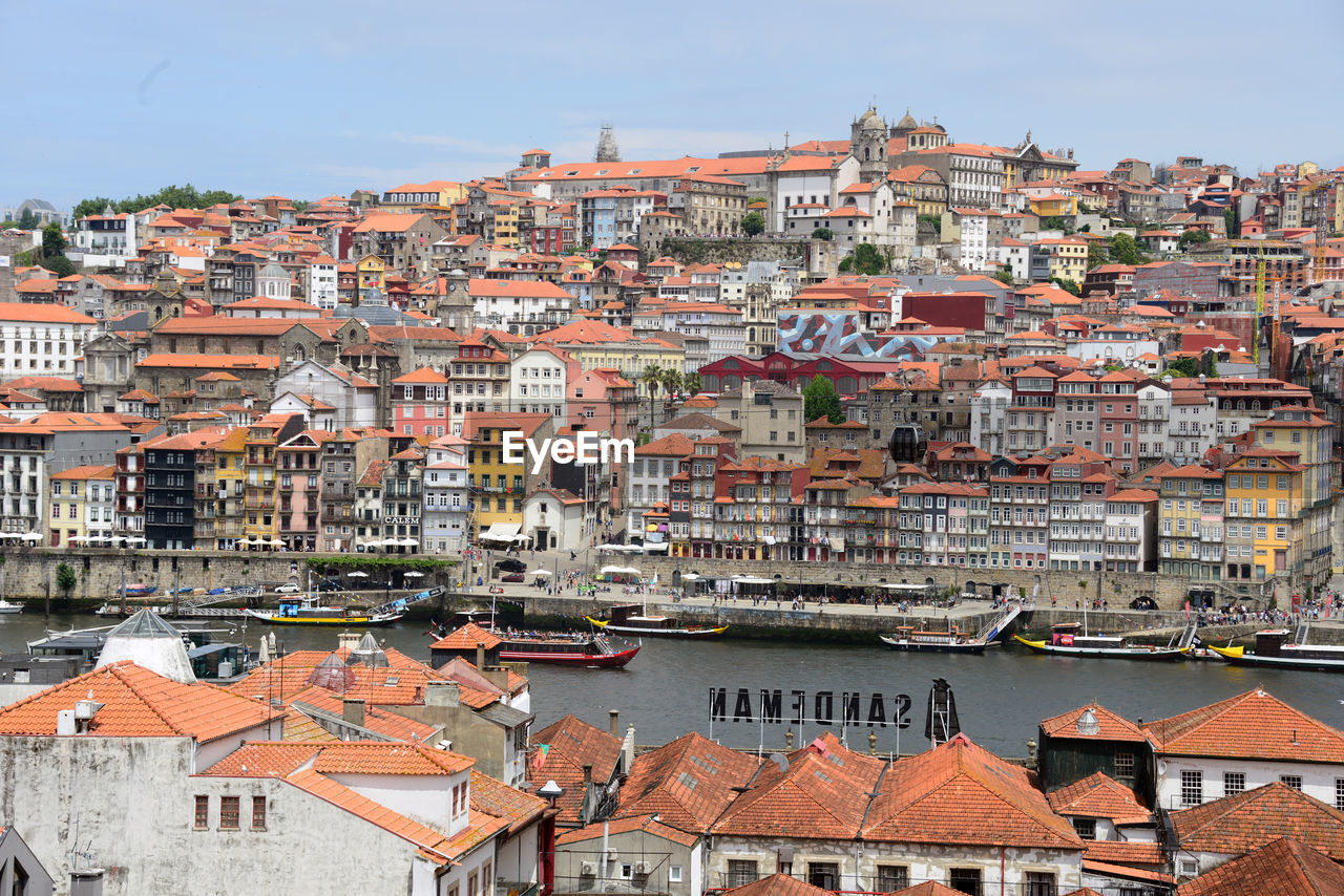 HIGH ANGLE VIEW OF TOWNSCAPE BY RIVER AGAINST SKY