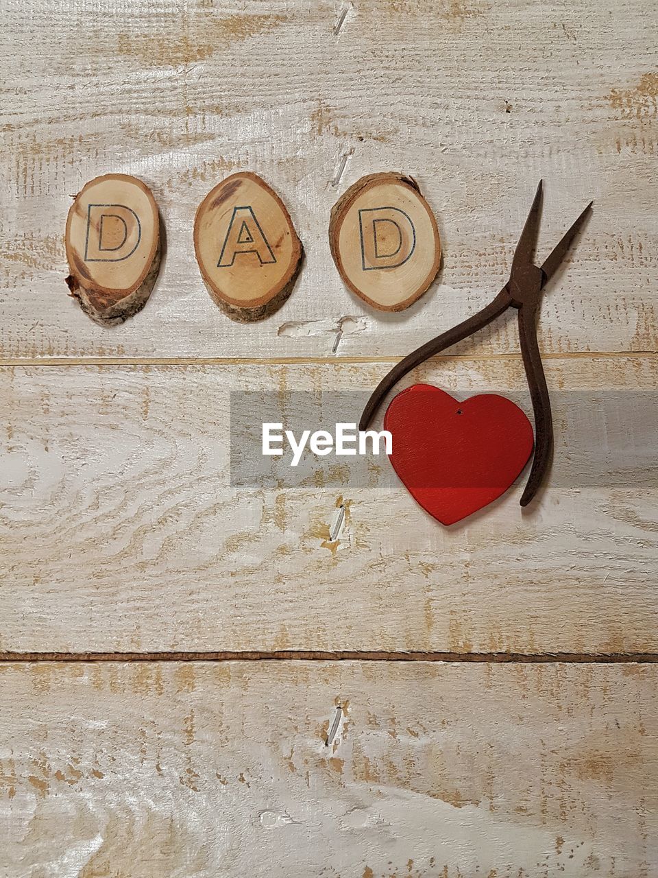 High angle view of dad alphabets by pliers and heart shape decoration on table