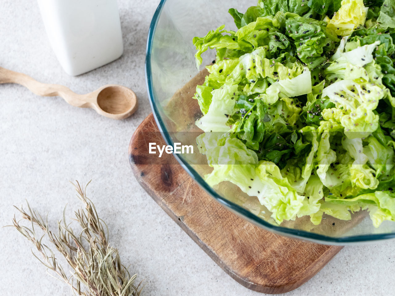 Bowl with freshly washed lettuce on wet white wooden background