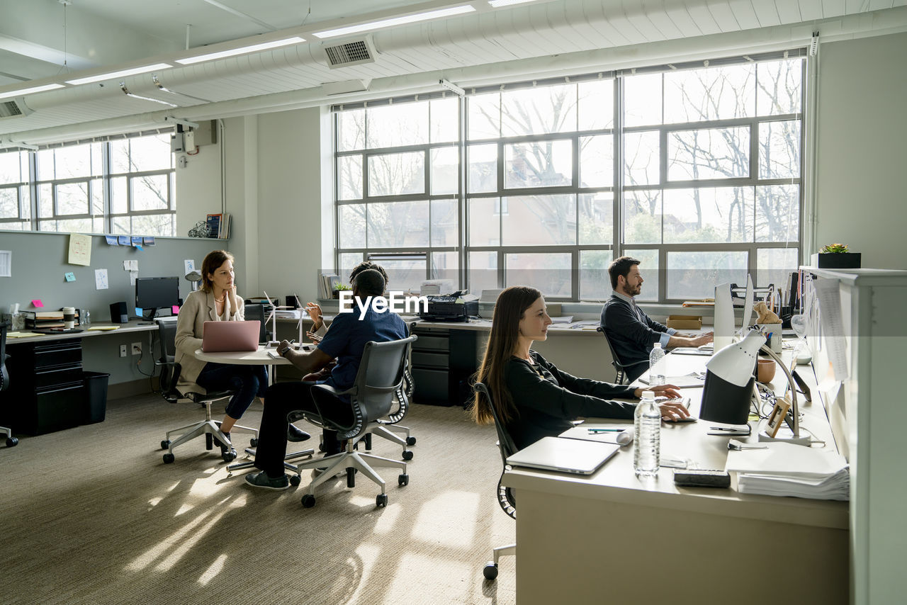 Business people discussing while sitting at desk in office