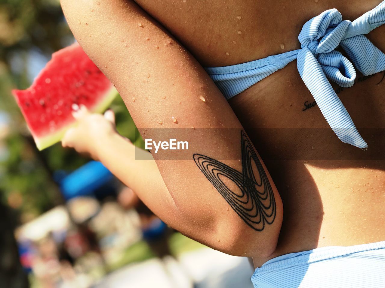 Midsection of teenage girl in bikini with tattoo on hand