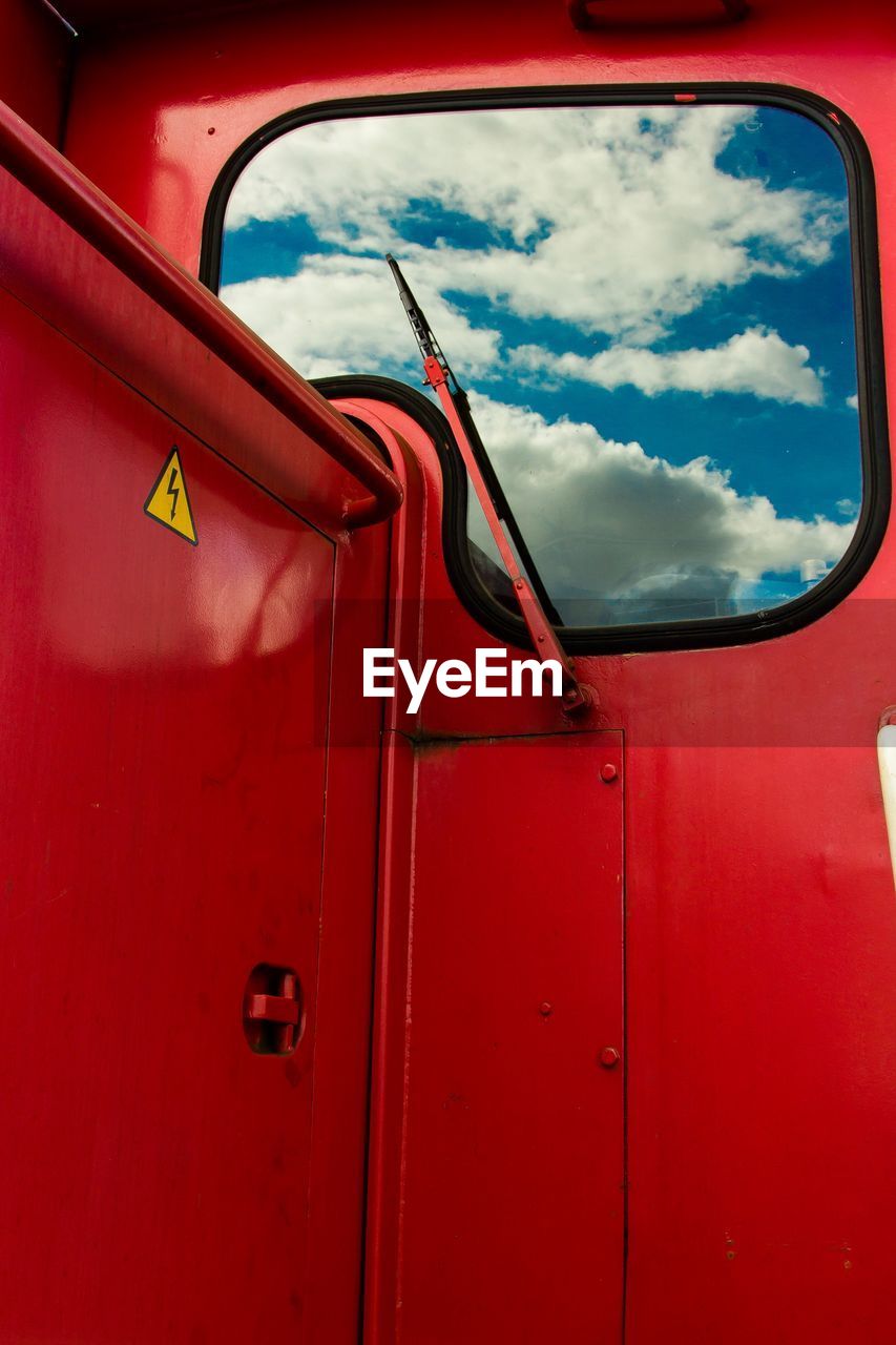 Close-up of cloudy sky seen through red vehicle