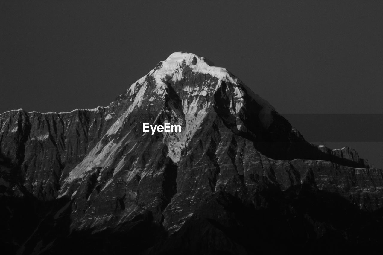 Low angle view of snowcapped mountains against clear sky