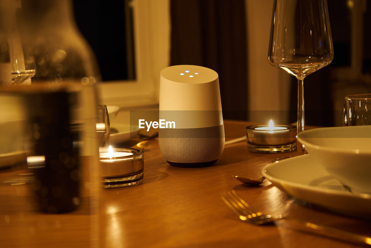 Close-up of google home and candles on table
