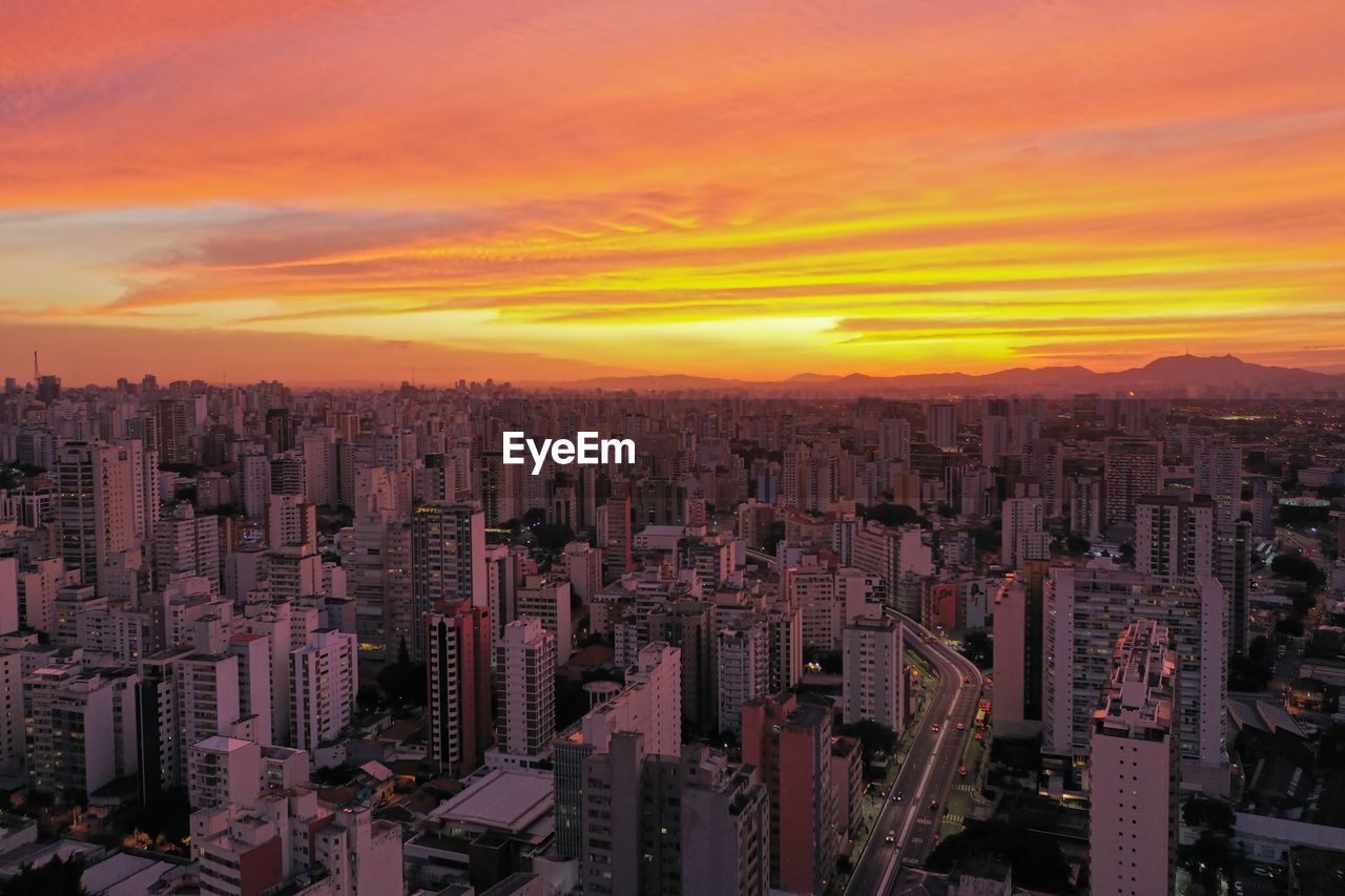 HIGH ANGLE VIEW OF BUILDINGS AGAINST SKY AT SUNSET