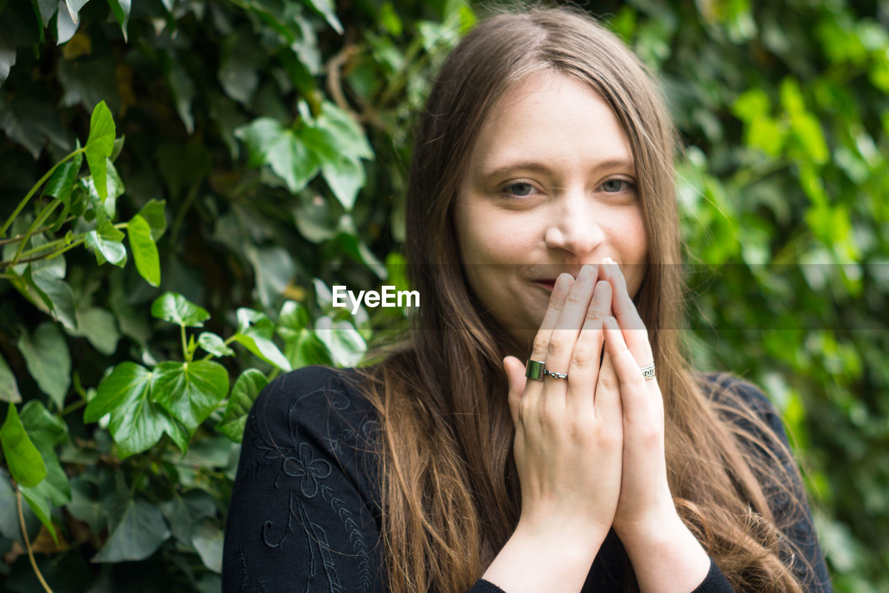 Portrait of young woman against plants