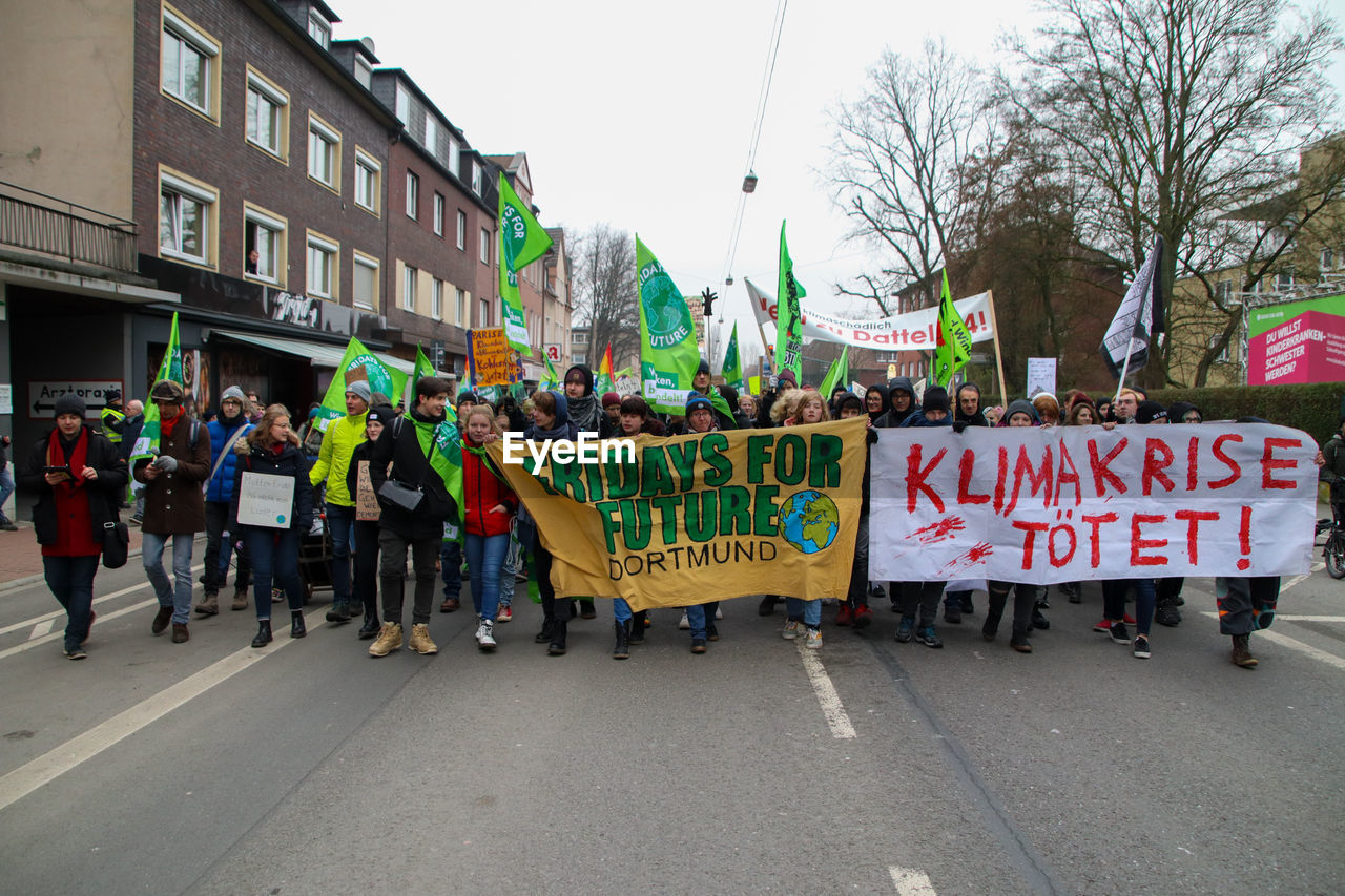 GROUP OF PEOPLE ON ROAD AGAINST BUILDINGS