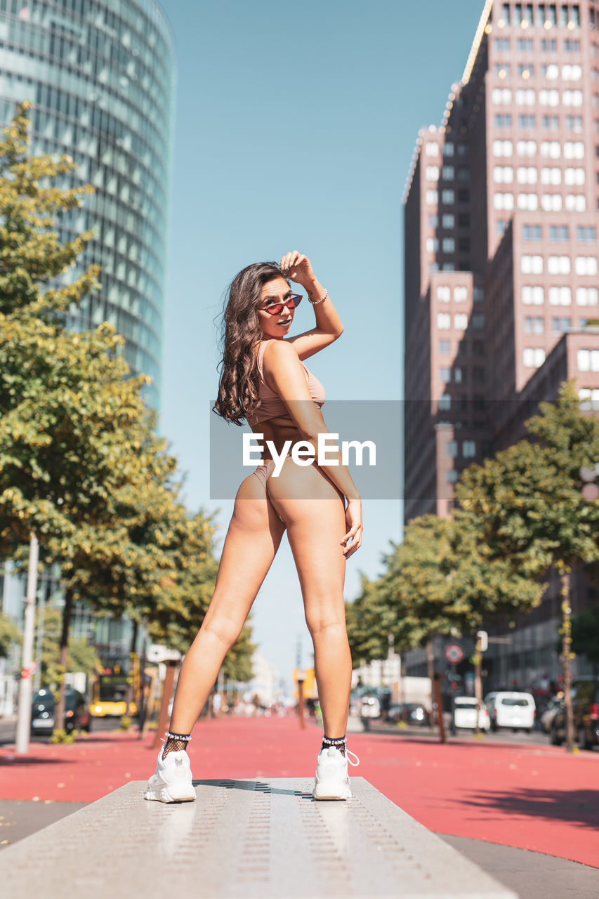 Young woman wearing bikini while standing against buildings in city