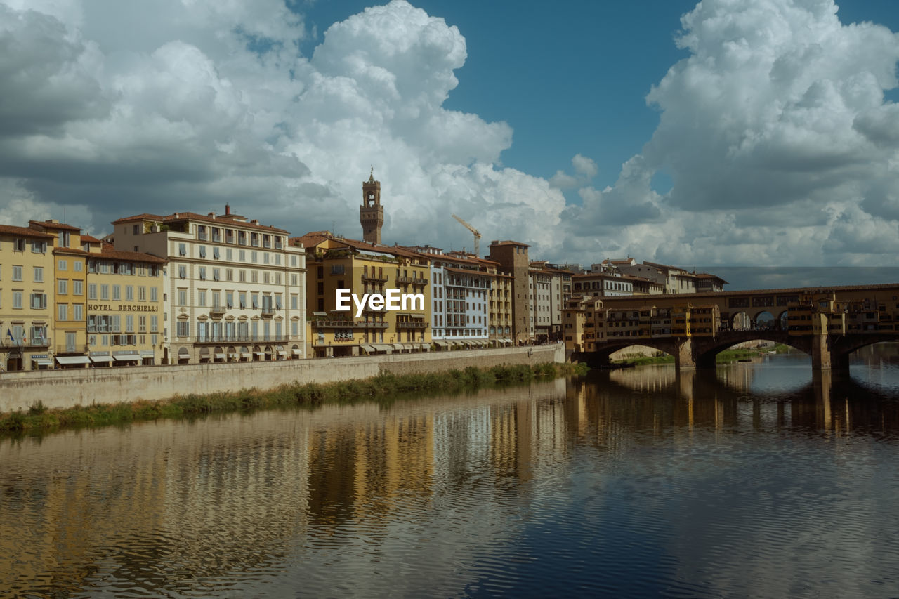 bridge over river by buildings against sky