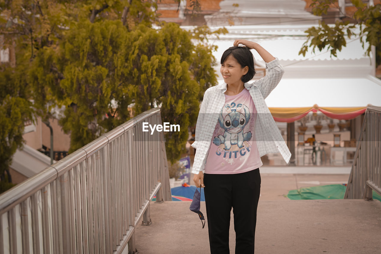 FULL LENGTH OF WOMAN STANDING BY RAILING