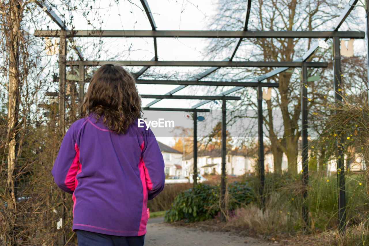 Rear view of a woman standing against trees