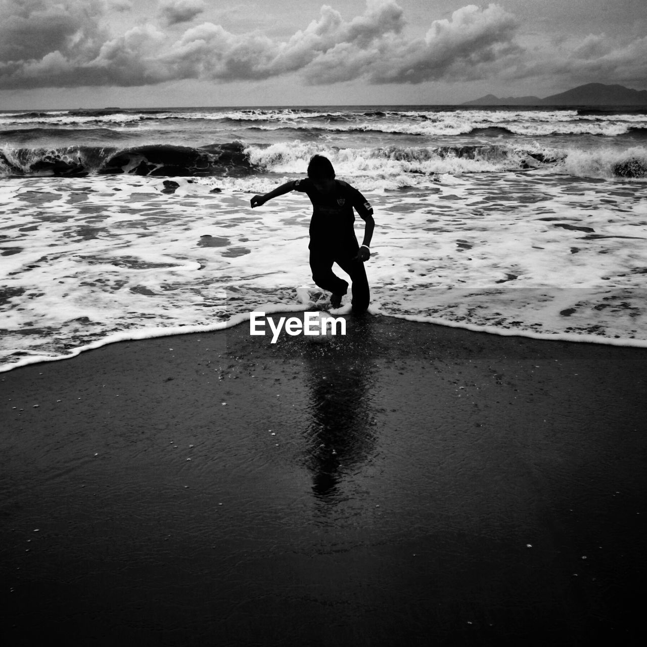 Silhouette man playing football at shore