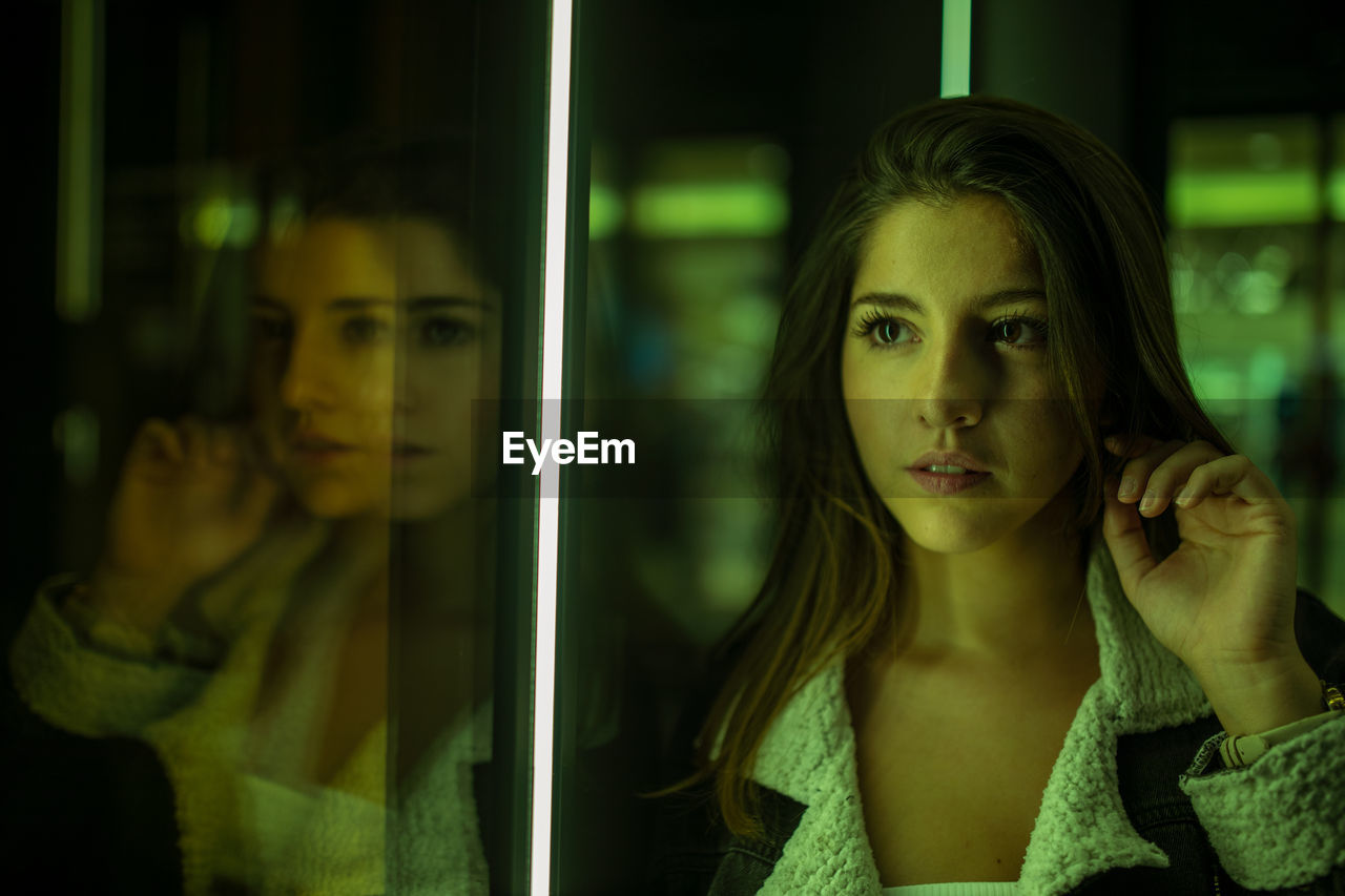 Young woman looking through glass window