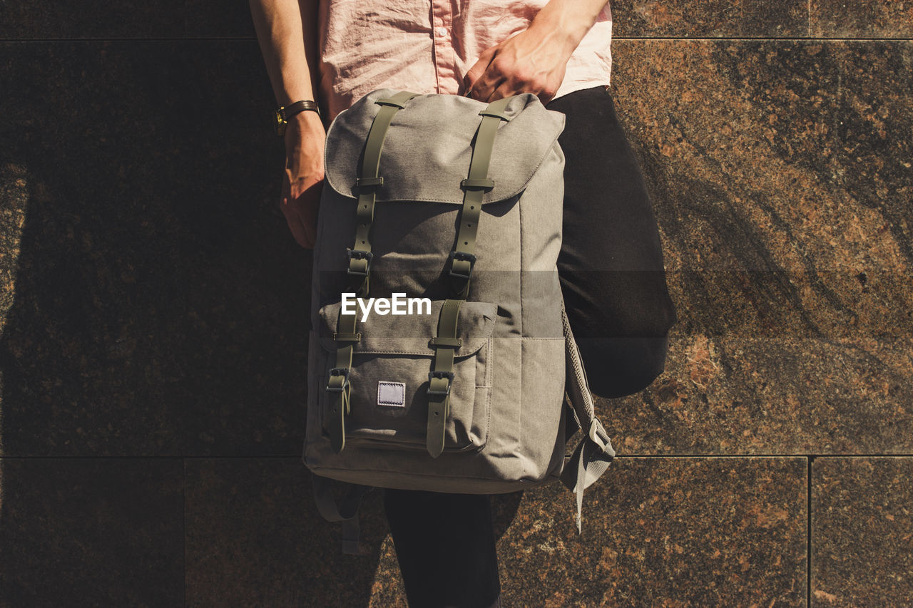 REAR VIEW OF MAN HOLDING UMBRELLA