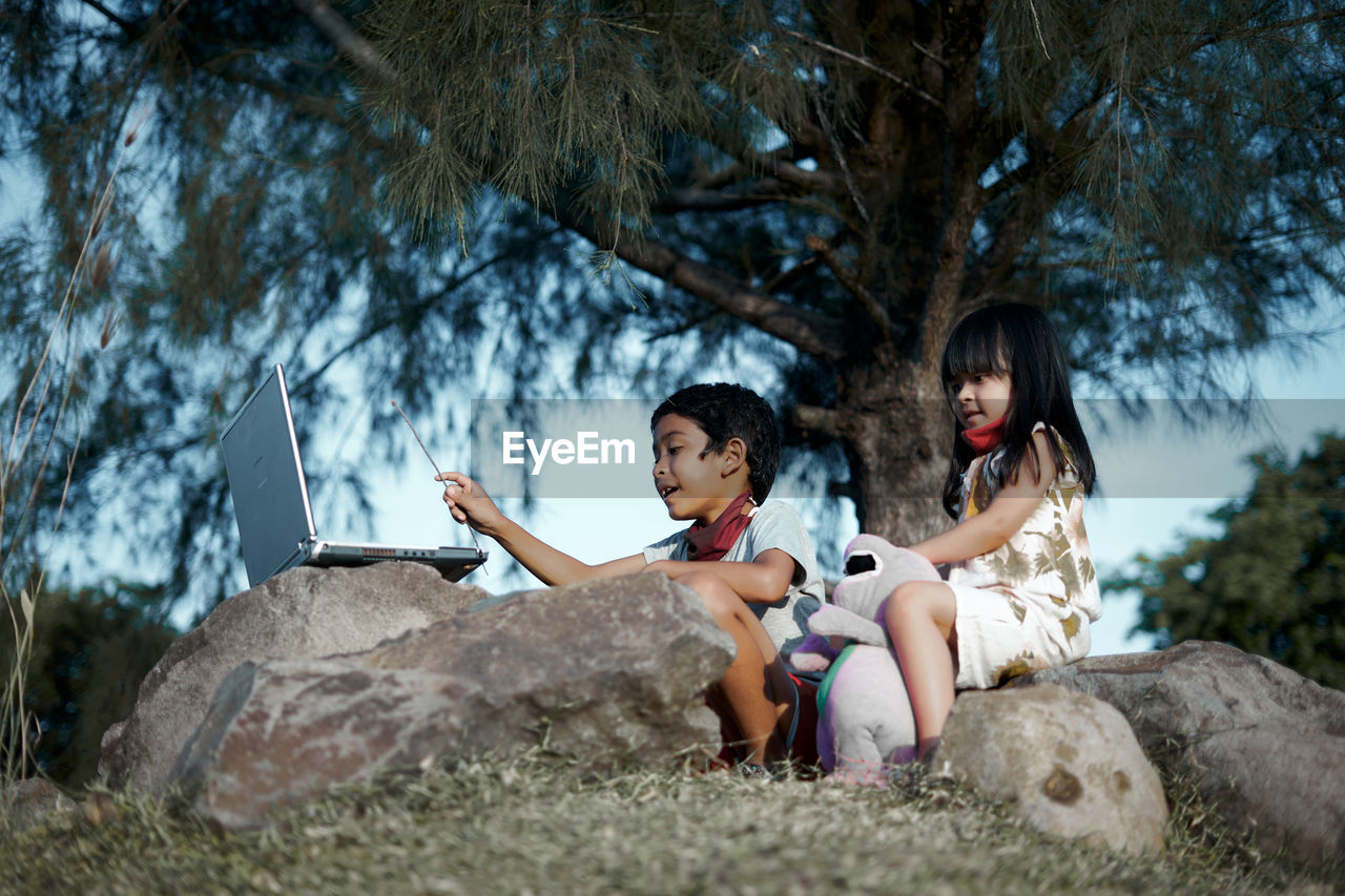 Women sitting on rock against trees