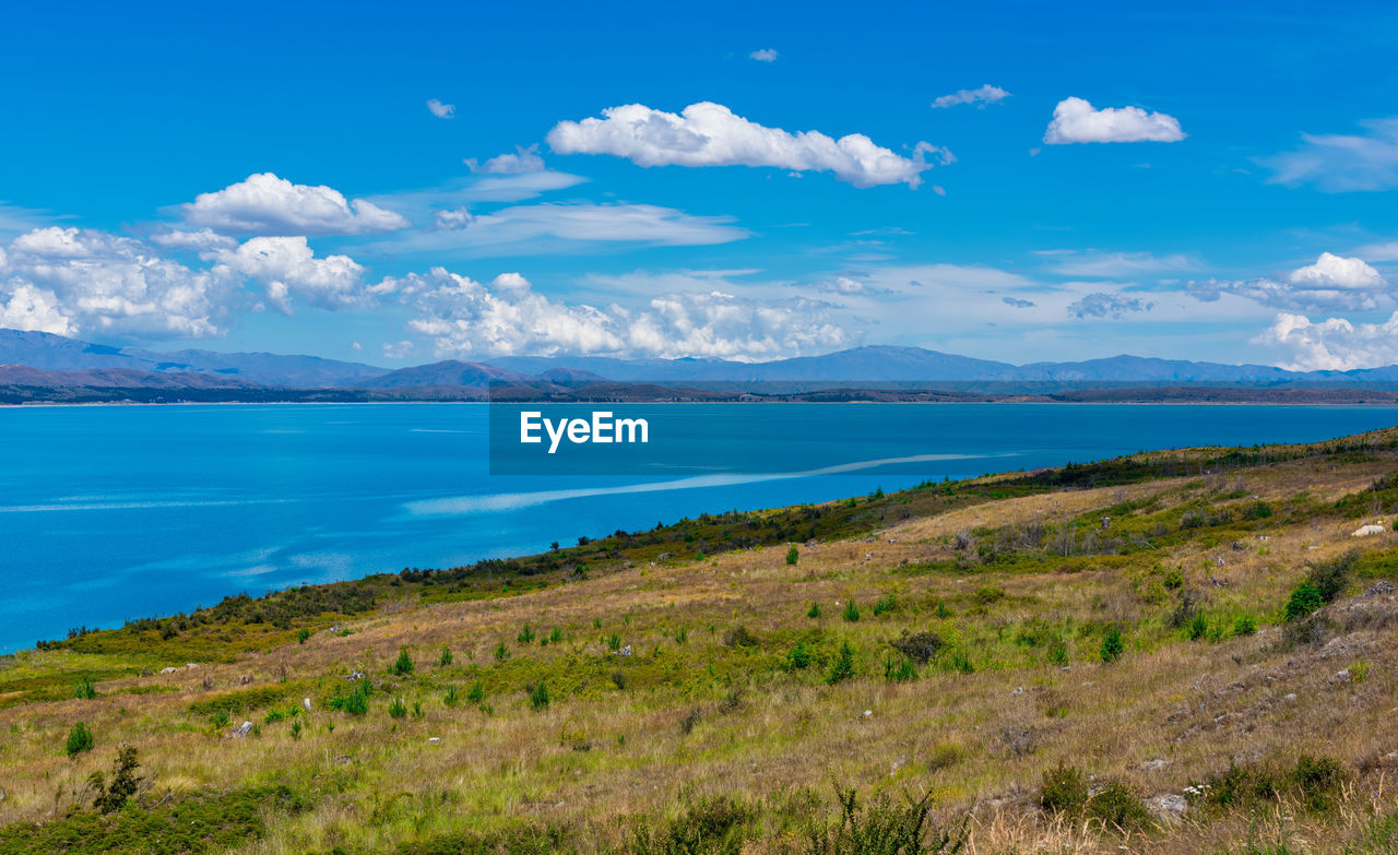 Scenic view of sea and mountains against blue sky