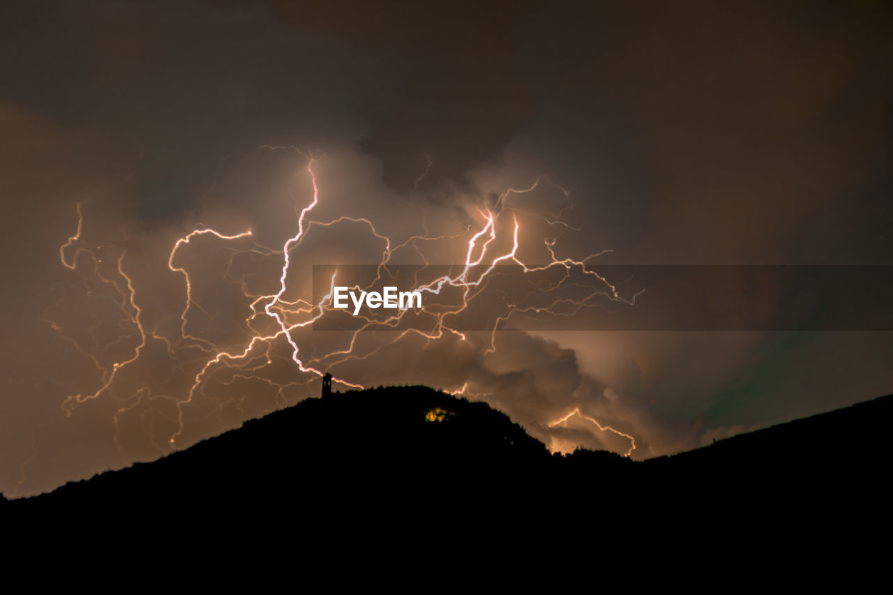 LOW ANGLE VIEW OF LIGHTNING AGAINST SKY DURING NIGHT