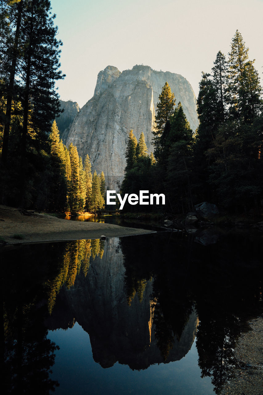 Scenic view of river by trees and mountains against sky