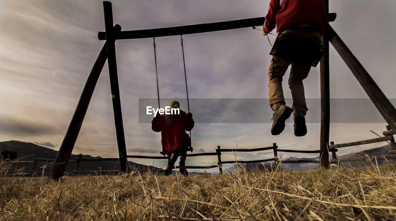 Rear view of people on swing against sky