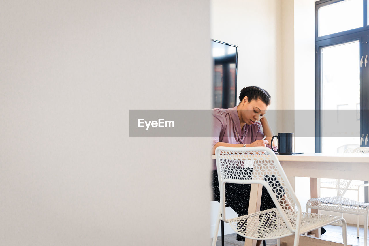 Young businesswoman writing at table in office