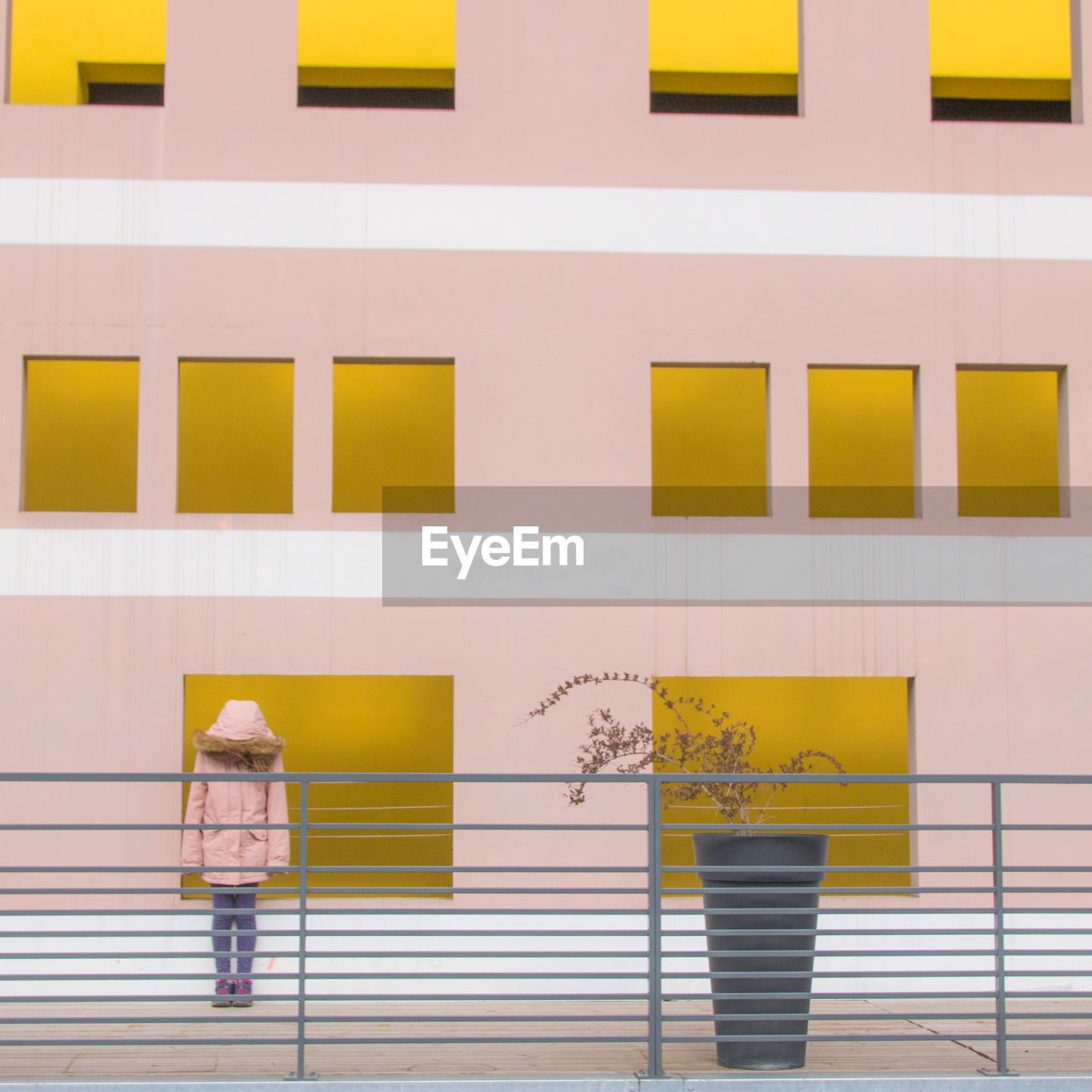 Full frame shot of yellow and pink wall against building with girl