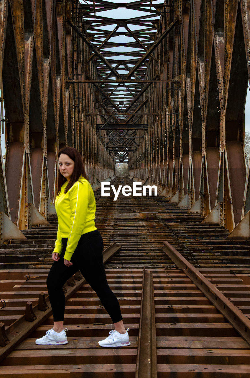 Full length of young woman walking on railway bridge