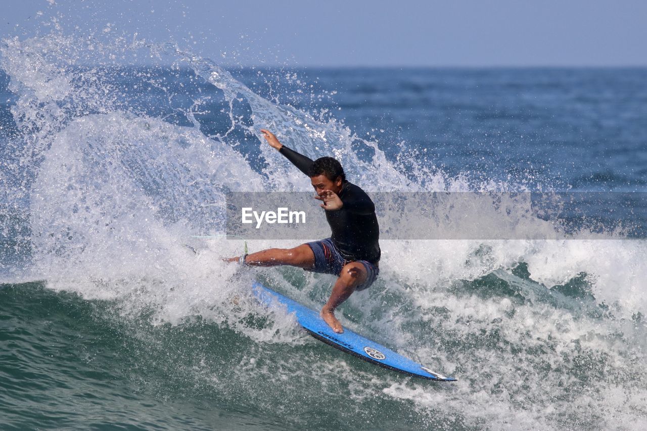 MAN SURFING ON SEA WAVES