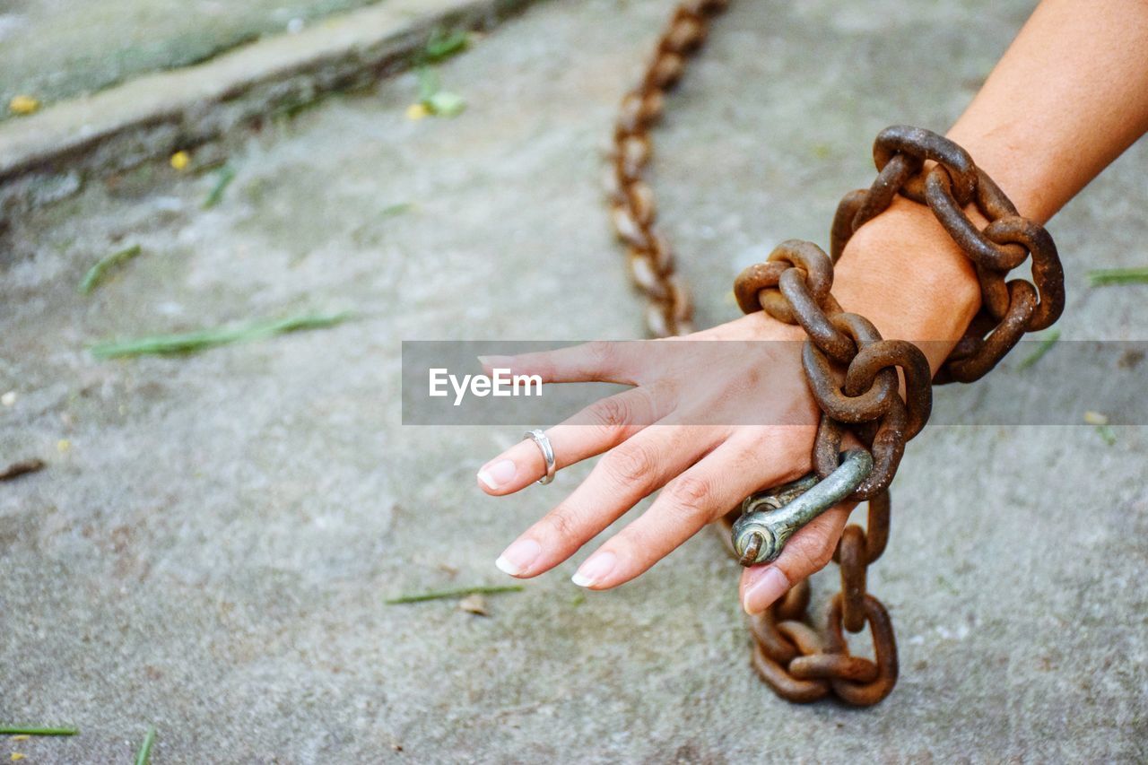 Close-up of hand tied with metal chain