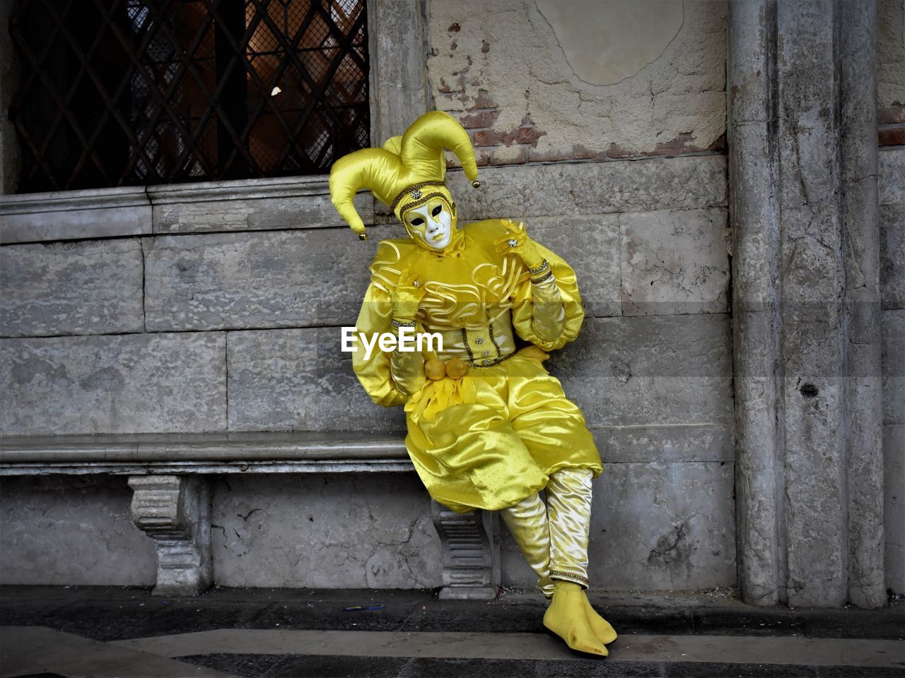 Full length of person wearing yellow costume while sitting against wall