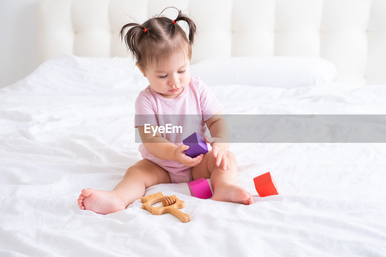 portrait of cute girl playing with toy on bed