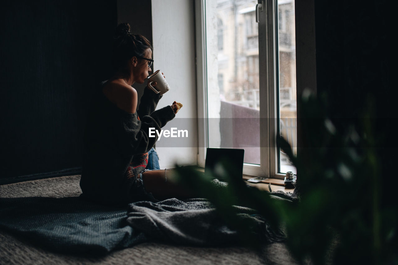 Side view of woman eating at home