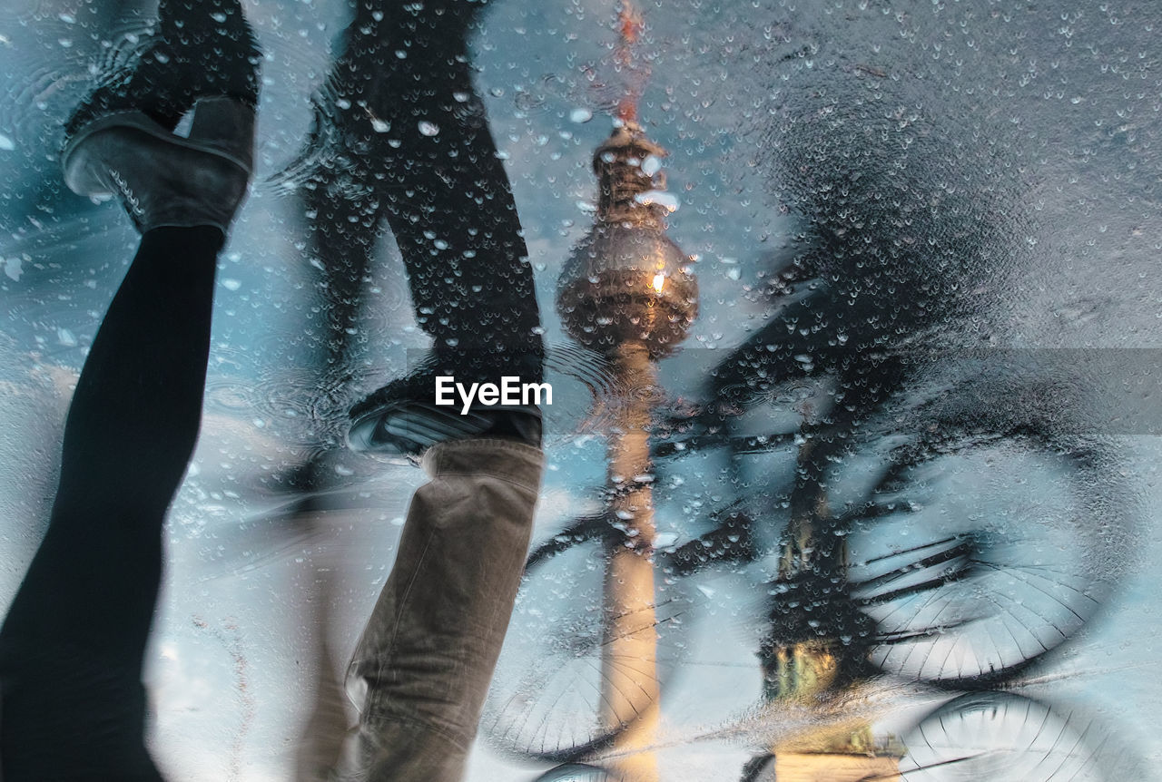 Reflection of  bicycle and pedestrians in puddle, television tower as background