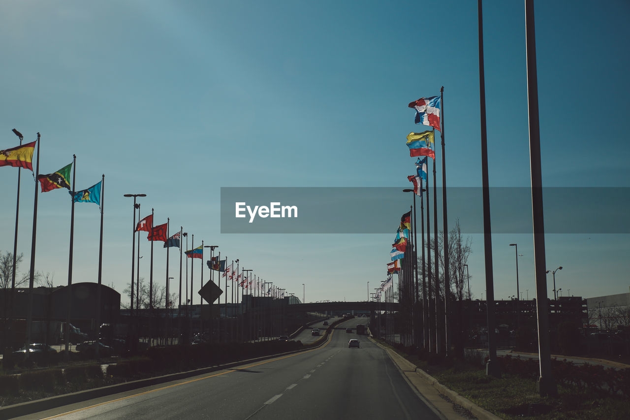 Road amidst various flags against sky