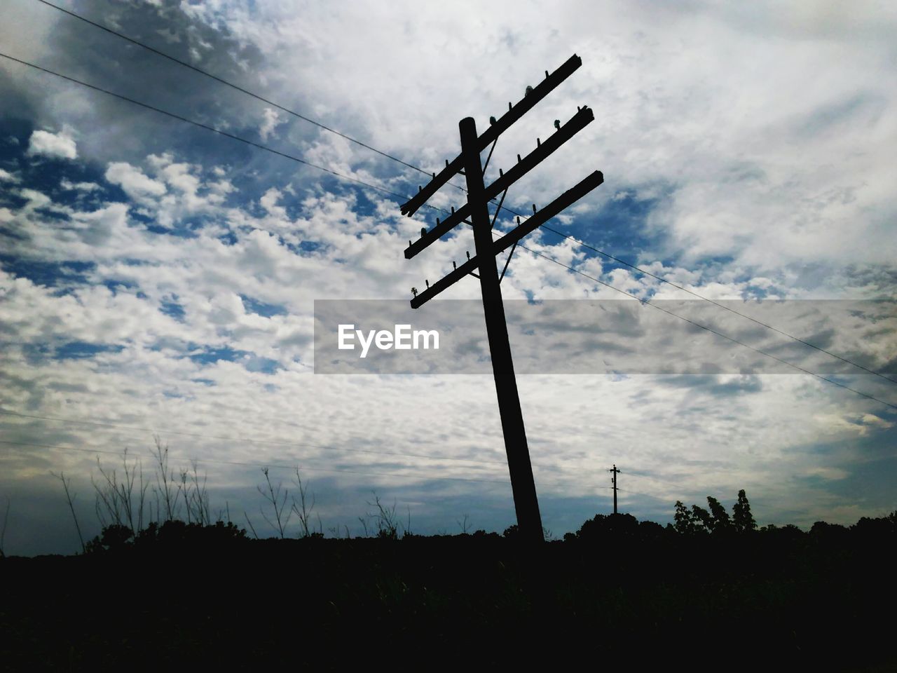 LOW ANGLE VIEW OF ELECTRICITY PYLONS AGAINST CLOUDY SKY