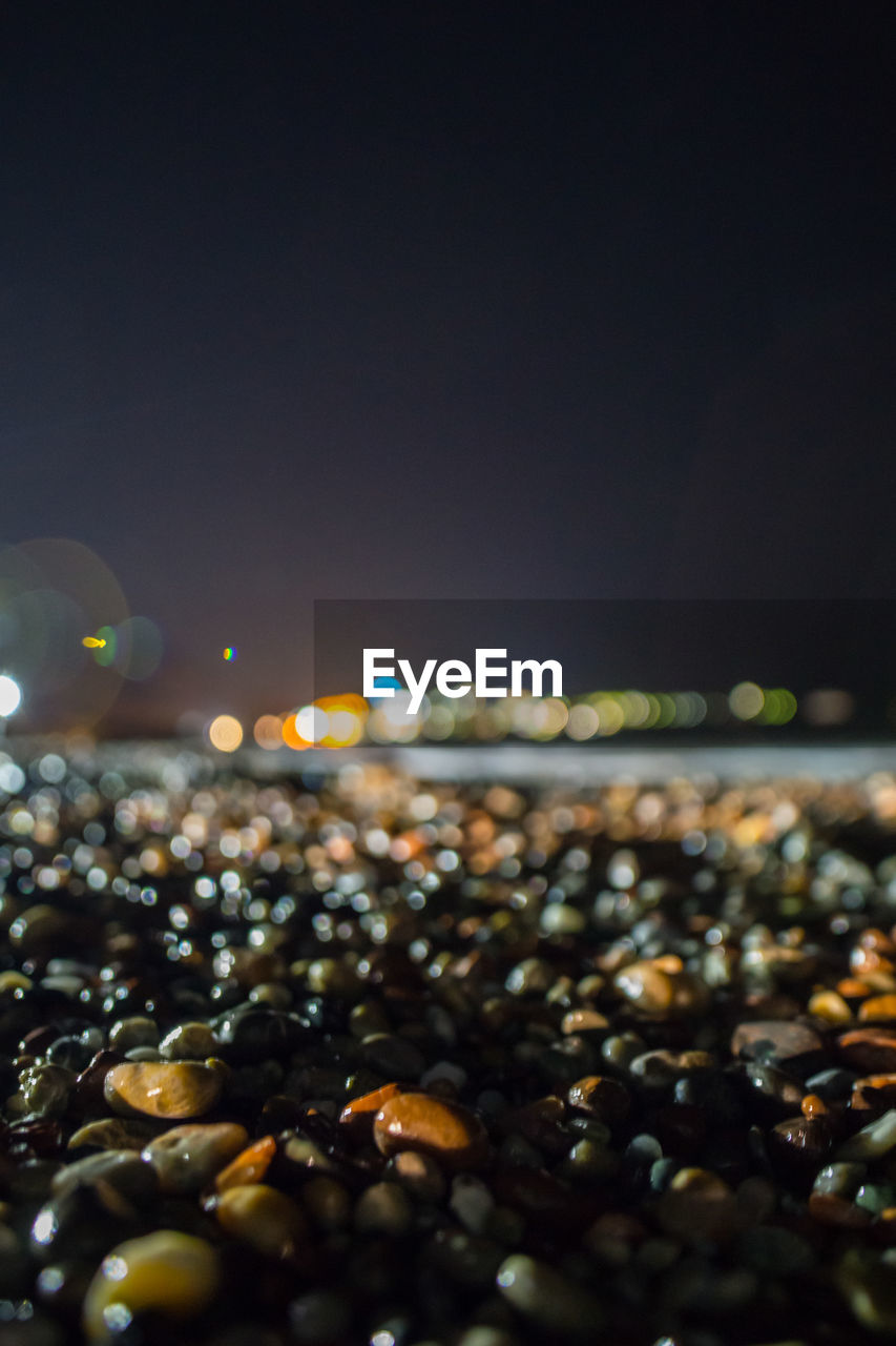 Close-up of pebbles at beach against sky at night