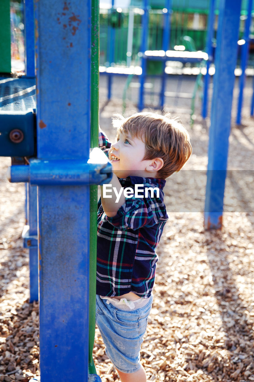 Modern colorful kids playground - swings, slides, steps and ladders.  little boy on swing and slide.