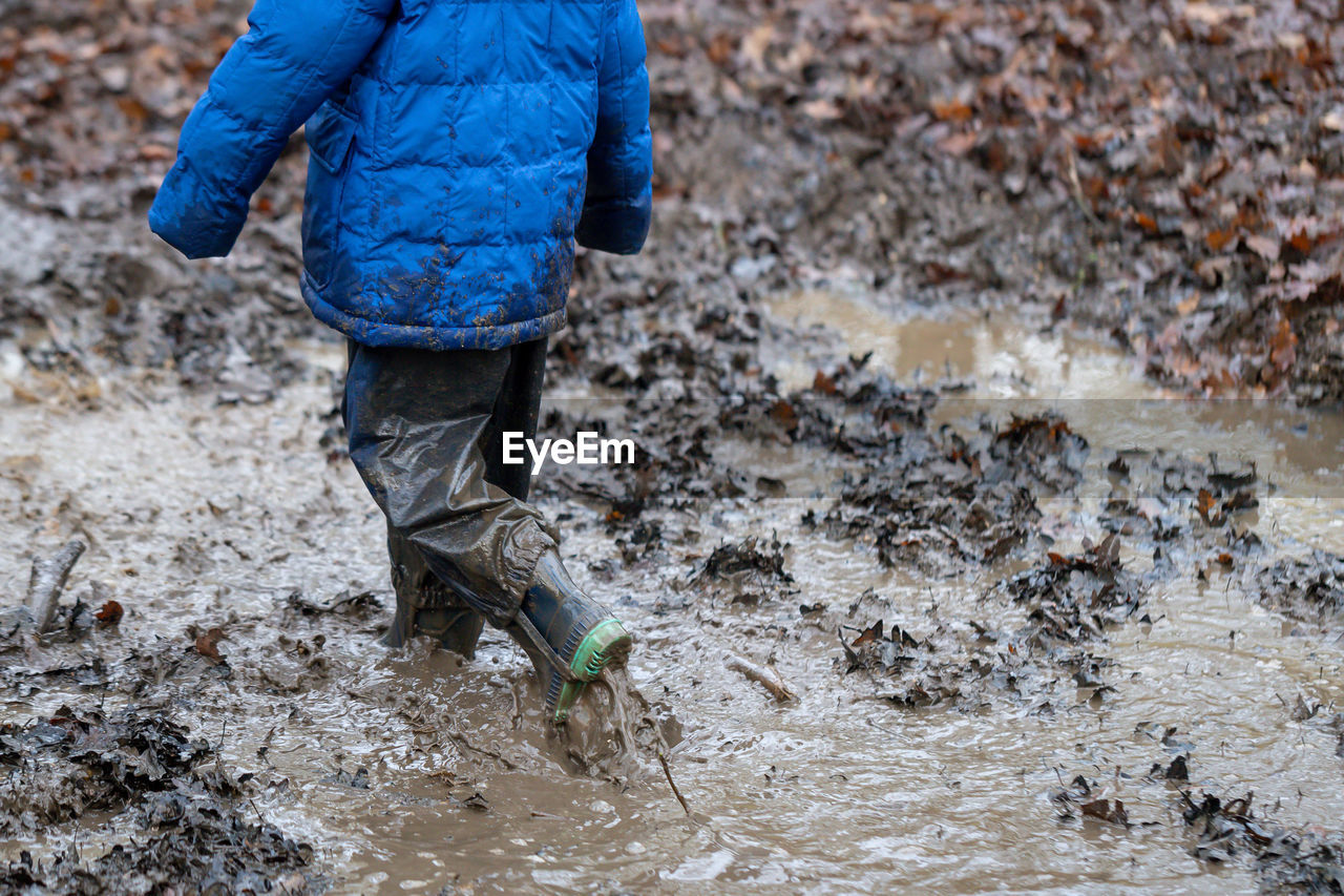 Low section of child walking in mud