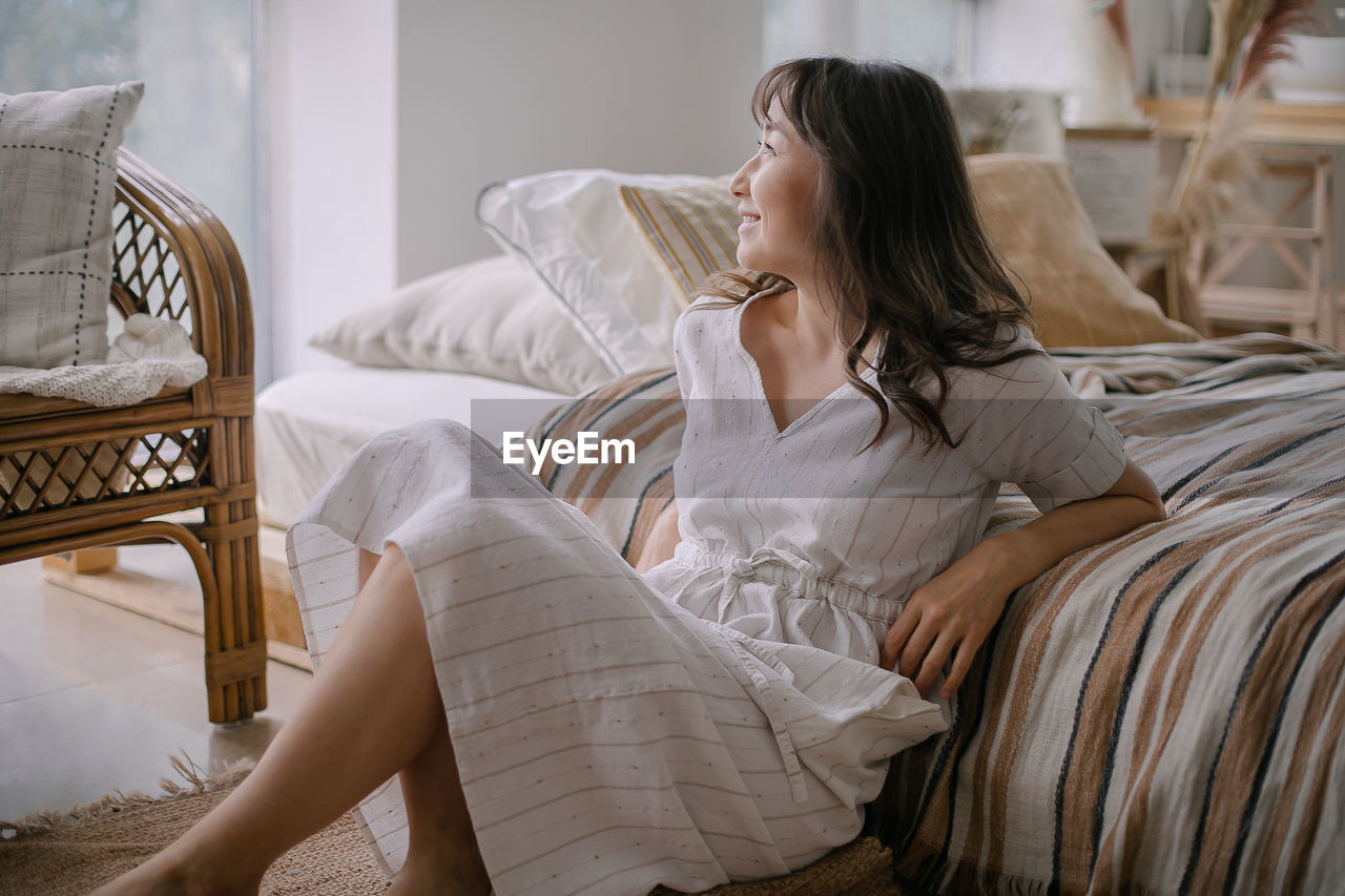 Young woman sitting on bed at home