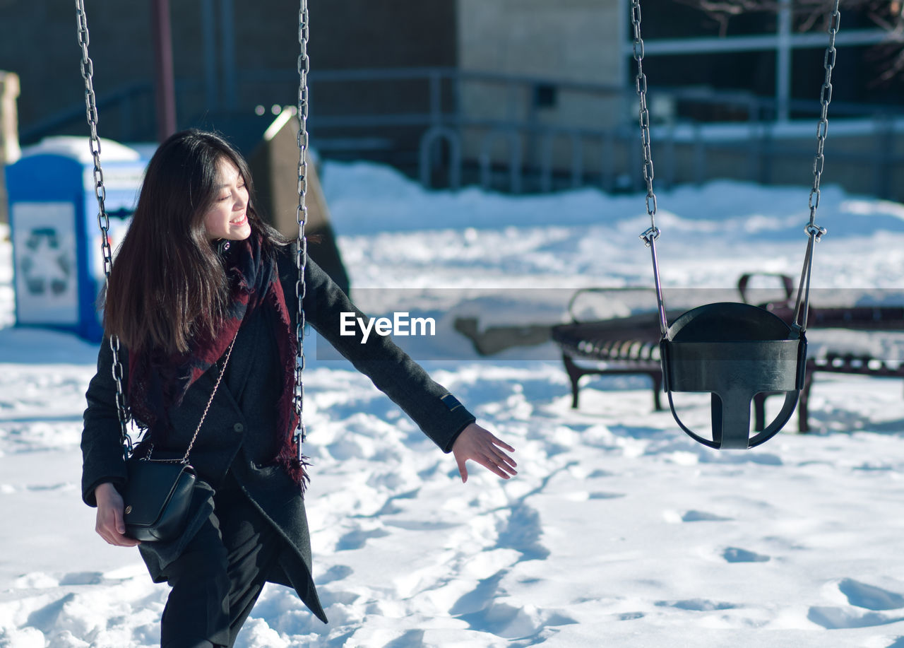 Woman sitting on swing during winter