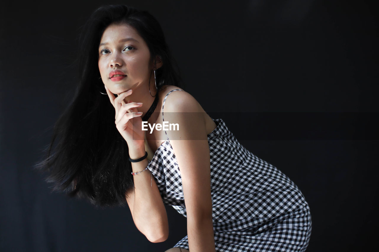 Beautiful woman looking away against black background