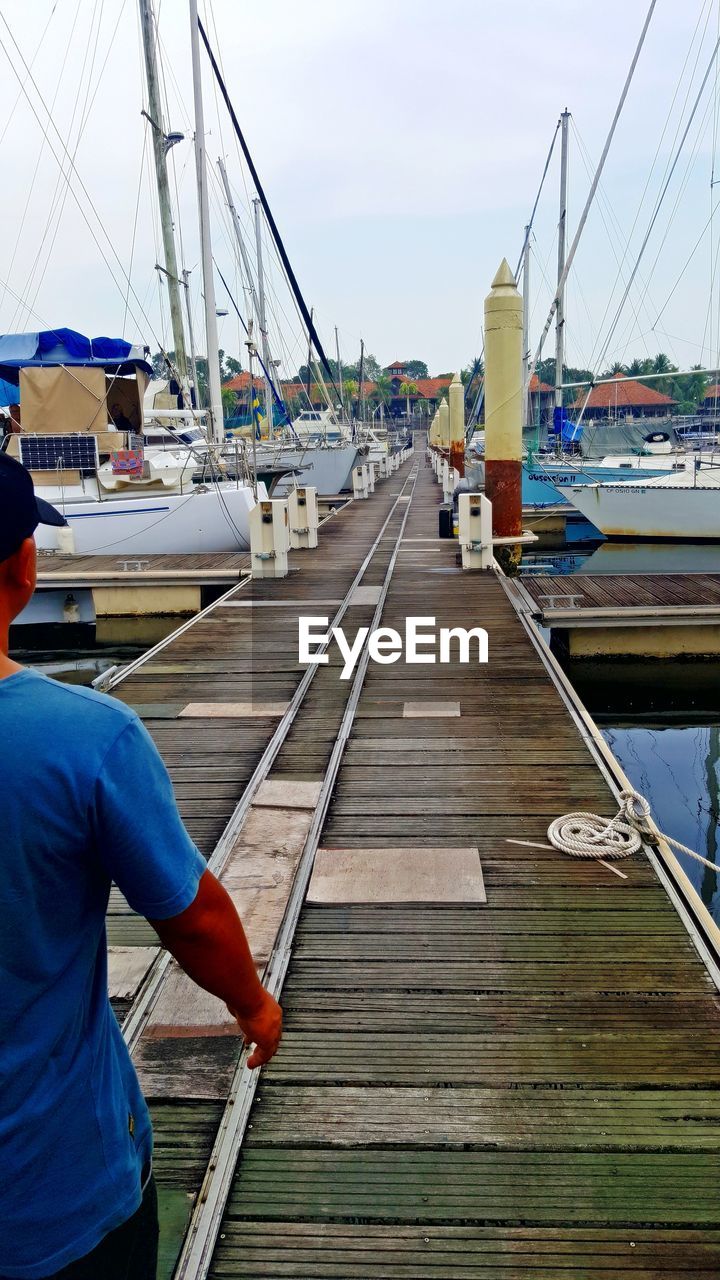 REAR VIEW OF WOMAN ON PIER AT HARBOR