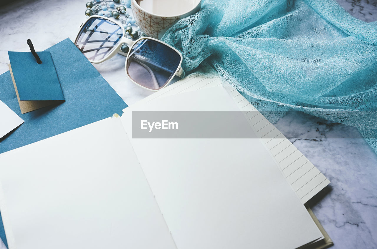 blue, indoors, high angle view, turquoise, table, paper, no people, art, still life, textile, furniture, glasses, copy space, close-up