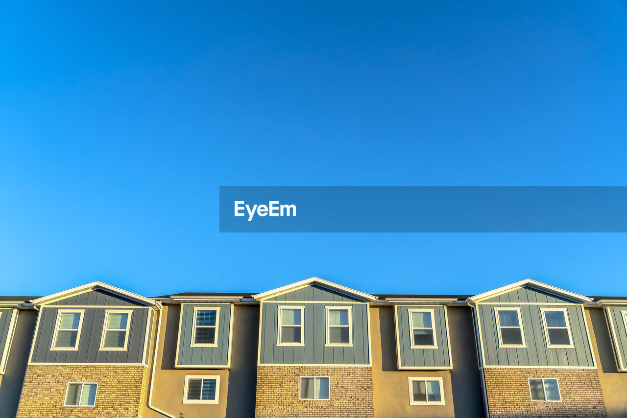 LOW ANGLE VIEW OF RESIDENTIAL BUILDING AGAINST BLUE SKY