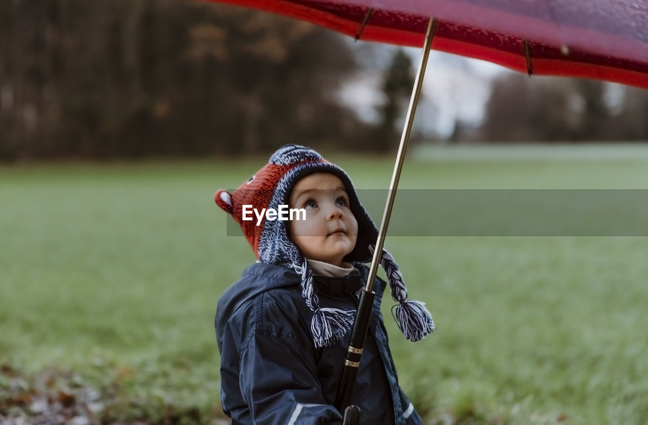 Close-up of girl holding umbrella while standing on field