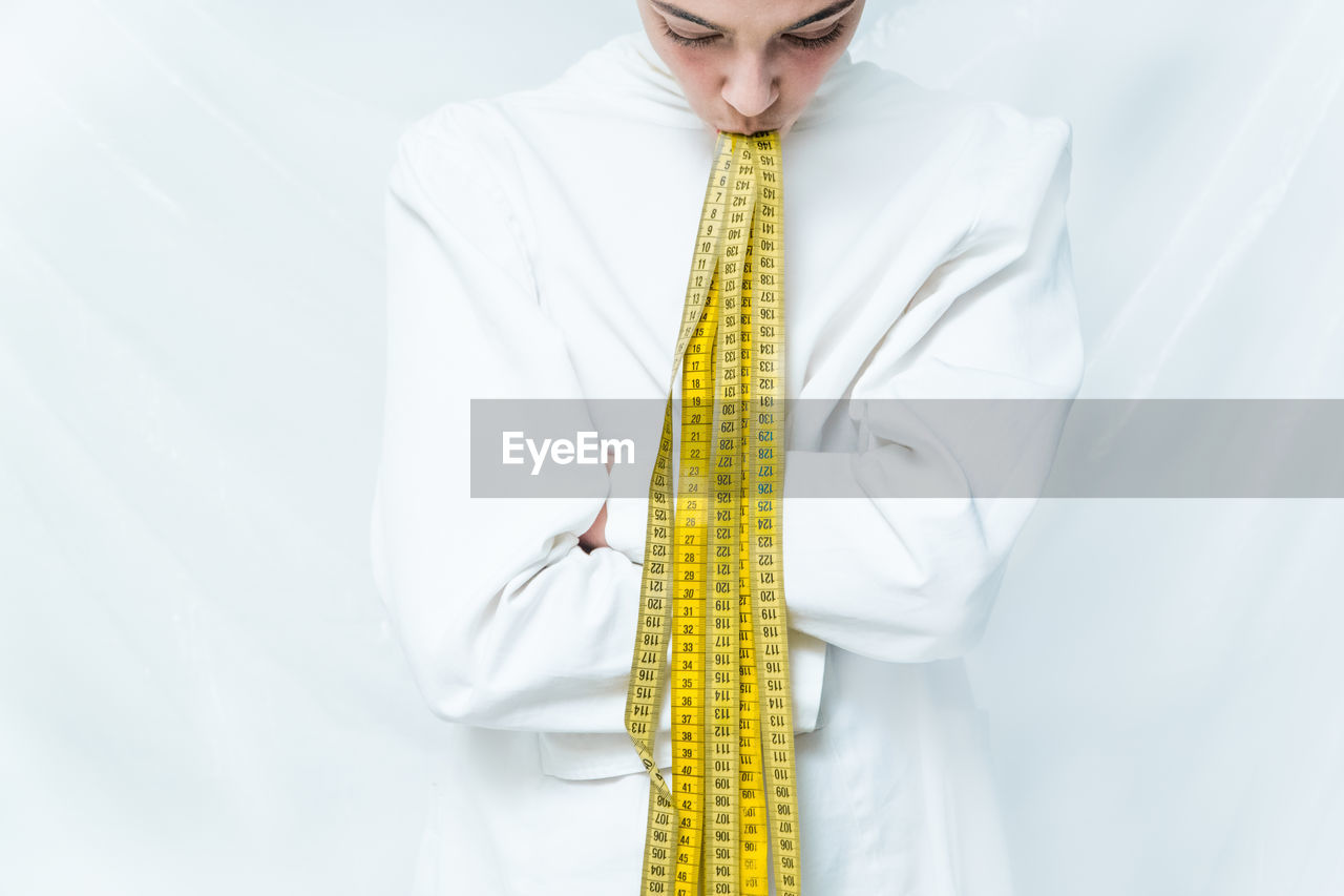 Midsection of man with yellow umbrella standing against white background